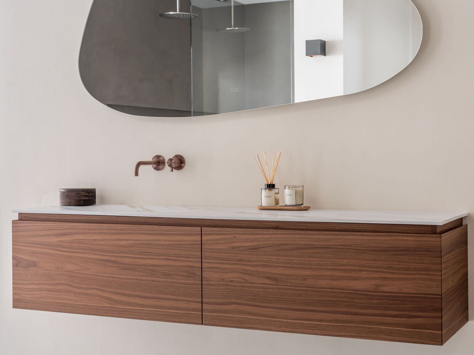 Notenhouten hangmeubel met een licht geaderd Solid Surface blad en een ovale spiegel