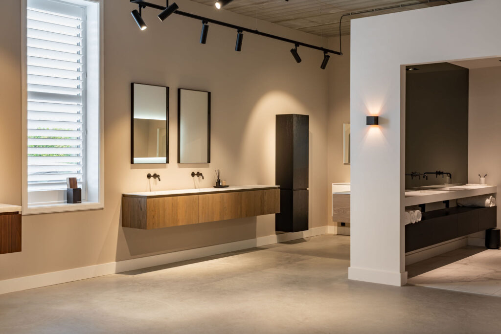 Showroomopstelling met twee wastafelbladen op onderkasten van eiken- en notenfineer, met spiegels aan de wand